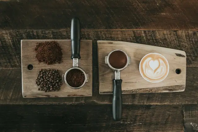 Coffee beans, ground coffee and a latte laid out on a board