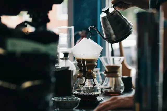 A barista slowly pouring water over a pour-over dripper