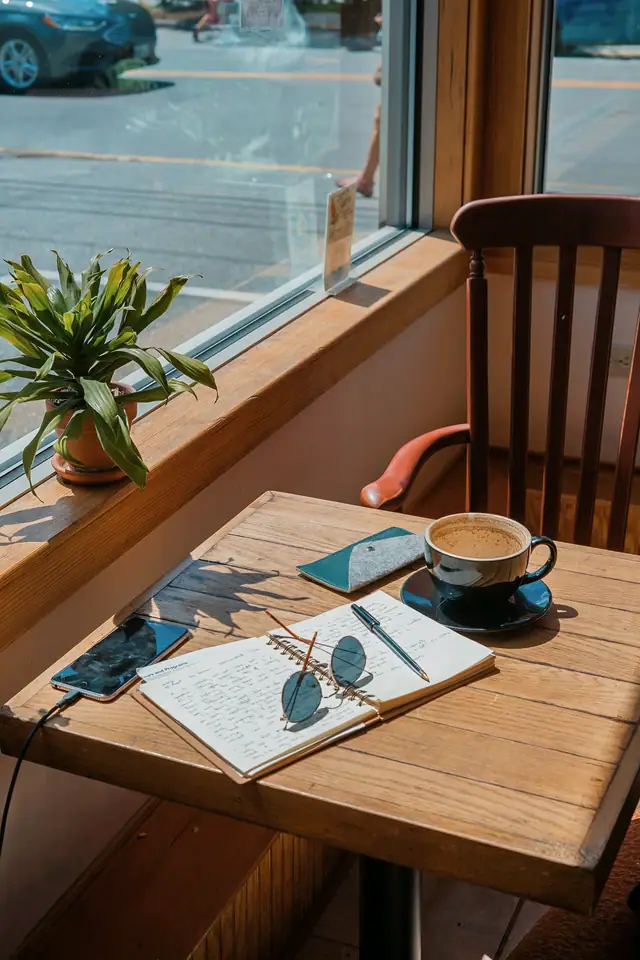 A window seat with a coffee, a notebook and a plant